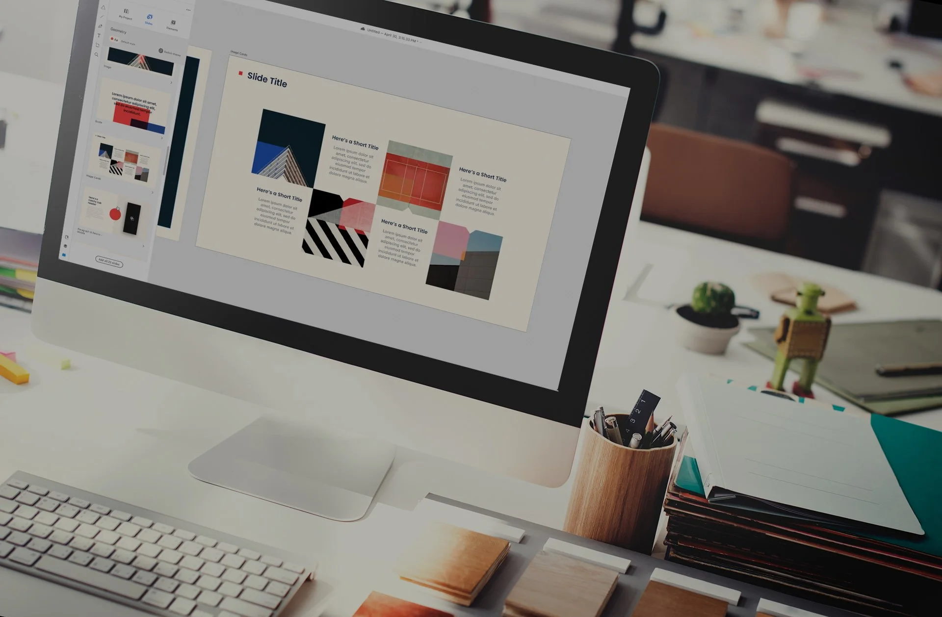 Desktop computer displaying an Adobe XD slide deck with geometric image cards, on a desk with design supplies and craft materials.